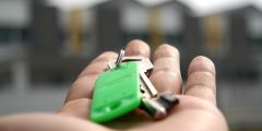 An image showing a hand outstretched with keys and a green keyring attached to it.